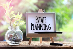 Window to the outside and on the frame some plants and a picture with the words Estate Planning symbolizing plan for your future contemplating your home