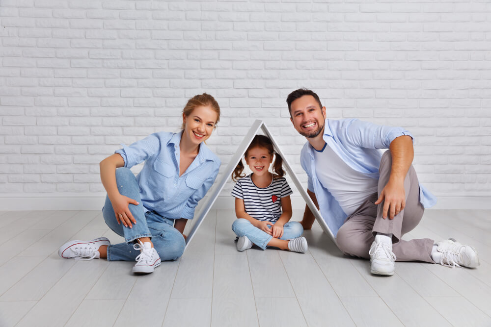 Parents sitting together covering their child with a wooden roof