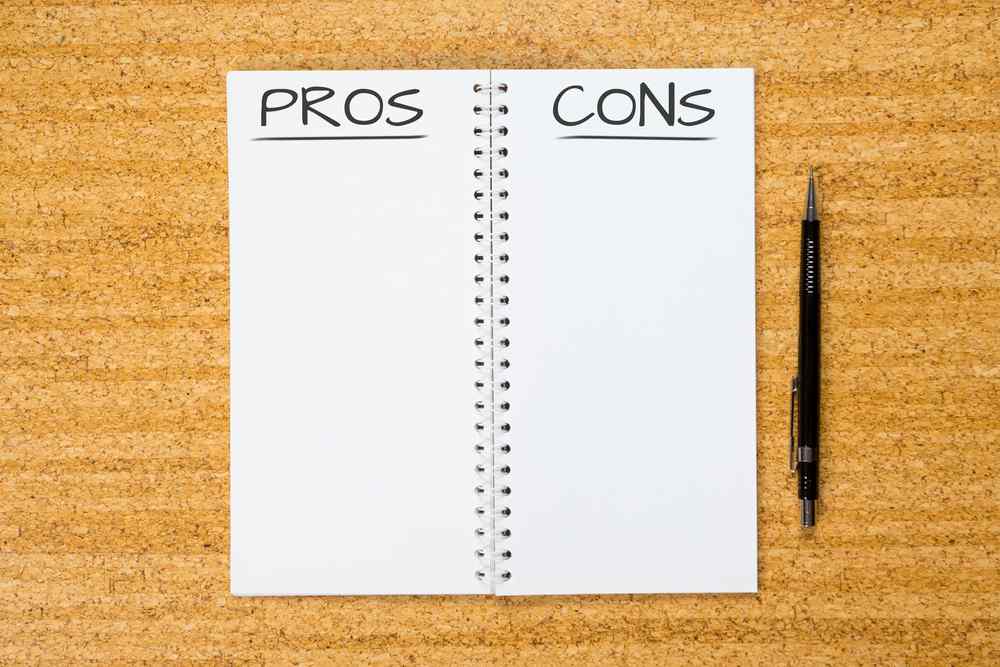 Note book with words pros and cons written next to each other and a pen on the side