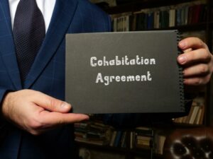 Man in suit holding a notebook with inscription in silver words that say cohabitation agreement