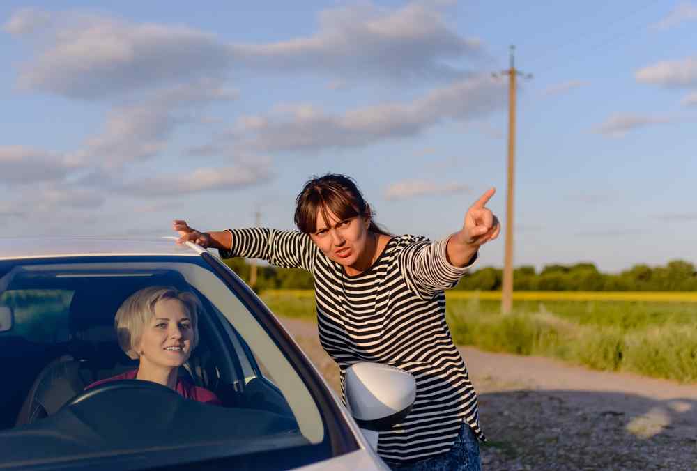 Executor inside her car asking for directions to locating beneficiaries to a man on the road who is pointing to the front with his left hand